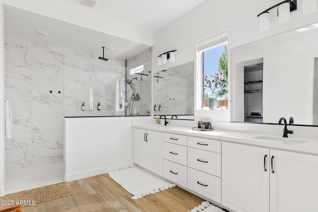 bathroom featuring a marble finish shower, wood finished floors, and double vanity