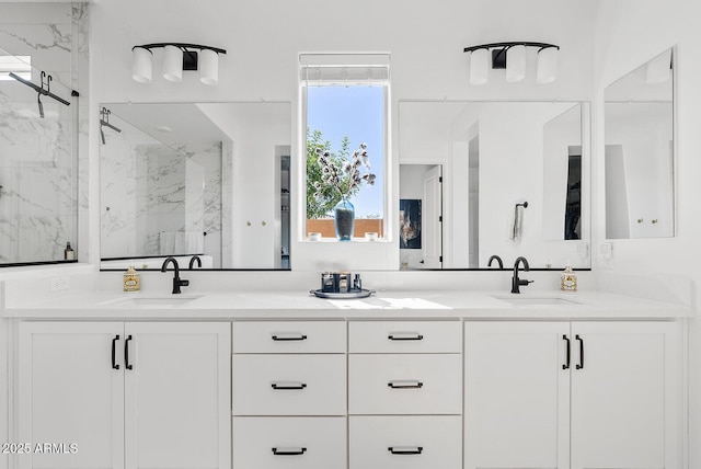 bathroom with a marble finish shower and double vanity