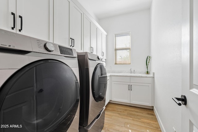 laundry room with washer and dryer, cabinet space, light wood-style flooring, and baseboards