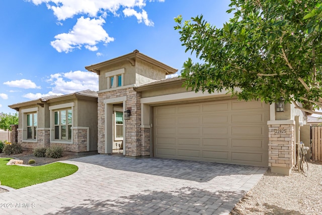 prairie-style house featuring stucco siding, stone siding, decorative driveway, an attached garage, and fence