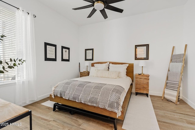 bedroom featuring light wood-type flooring, baseboards, vaulted ceiling, and ceiling fan