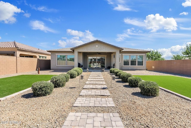 rear view of property with a ceiling fan, a fenced backyard, stucco siding, and a patio area