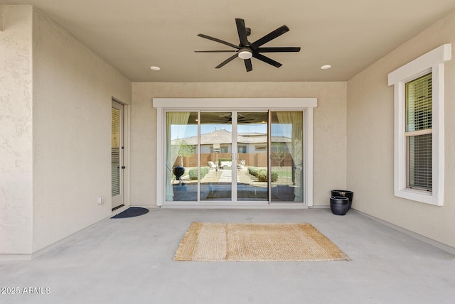property entrance with a ceiling fan, stucco siding, and a patio area