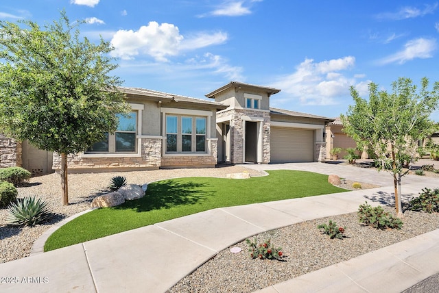 prairie-style home with stone siding, stucco siding, a garage, driveway, and a front lawn