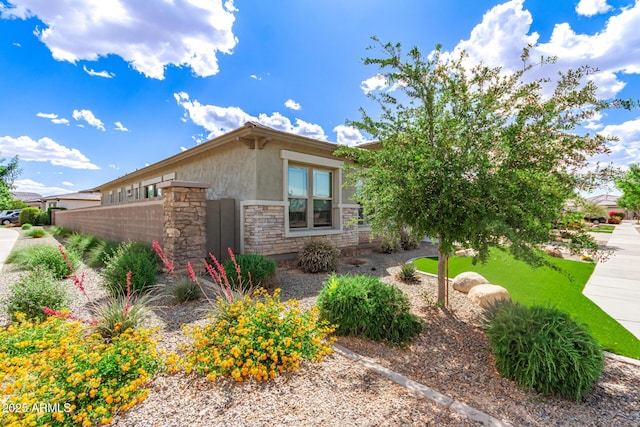 view of home's exterior featuring stone siding, stucco siding, and fence