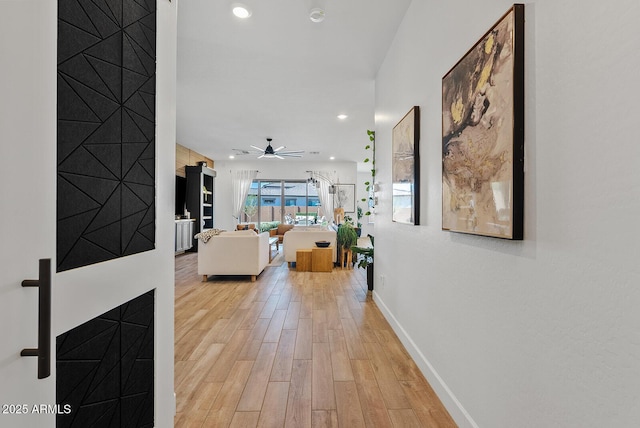 hallway featuring light wood-type flooring, baseboards, and recessed lighting
