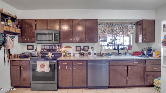 kitchen with light tile patterned floors, appliances with stainless steel finishes, dark brown cabinets, and sink