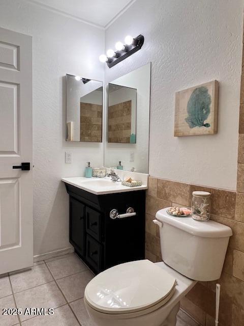 bathroom with tile patterned floors, toilet, tile walls, and vanity