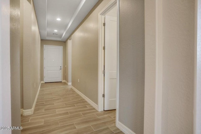 hallway featuring wood finish floors, baseboards, and recessed lighting