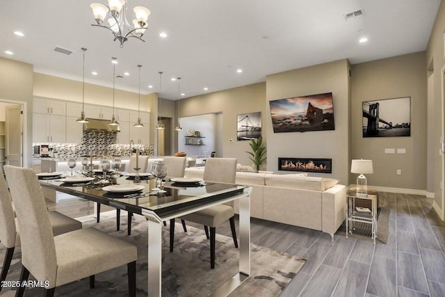 dining room with visible vents, wood tiled floor, and a glass covered fireplace