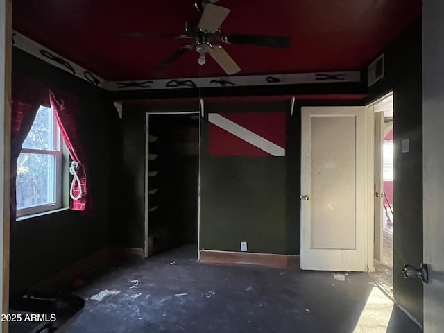 empty room with ceiling fan and concrete flooring