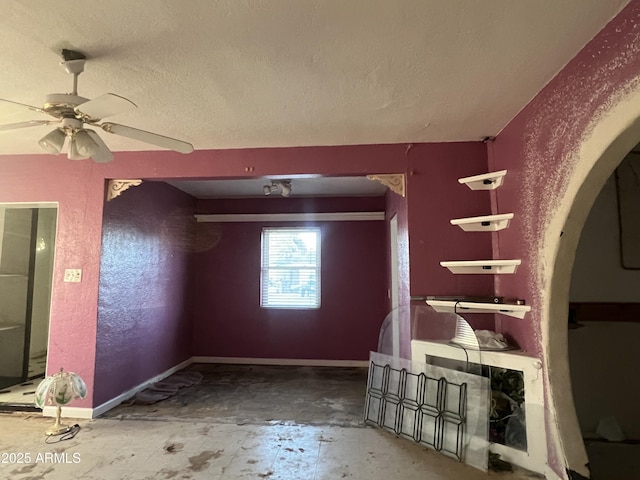 empty room with ceiling fan and a textured ceiling