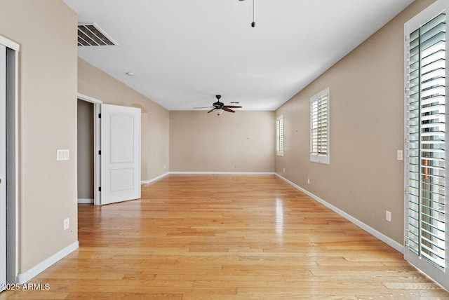 empty room featuring light wood finished floors, baseboards, visible vents, and a ceiling fan