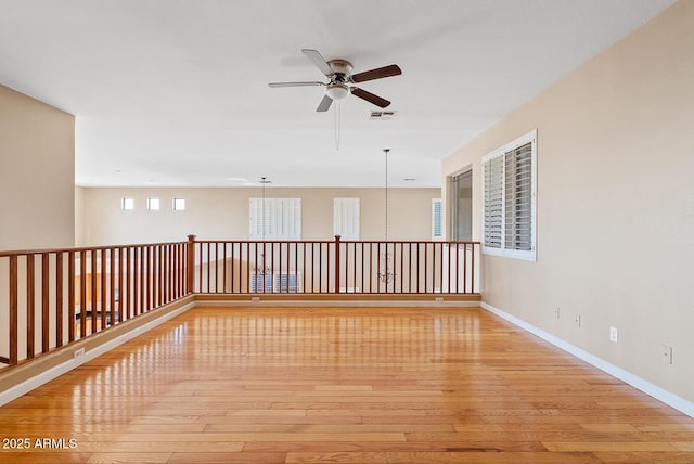 unfurnished room featuring light wood-style floors, visible vents, baseboards, and a ceiling fan