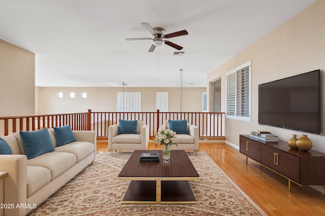 living room with visible vents, ceiling fan, light wood-style flooring, and baseboards