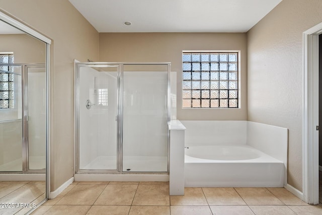 full bathroom with a stall shower, a garden tub, baseboards, and tile patterned floors