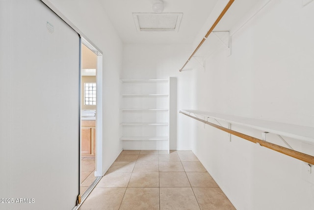 spacious closet featuring attic access and light tile patterned floors