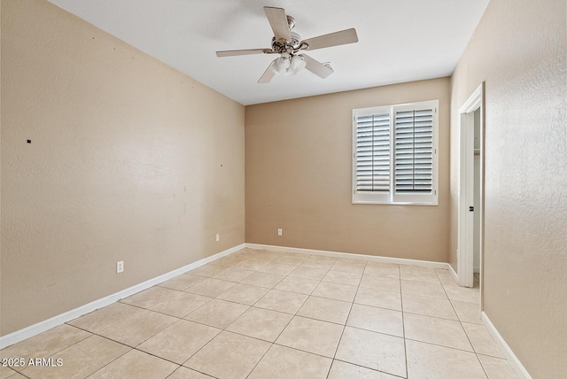 empty room with light tile patterned floors, baseboards, and a ceiling fan