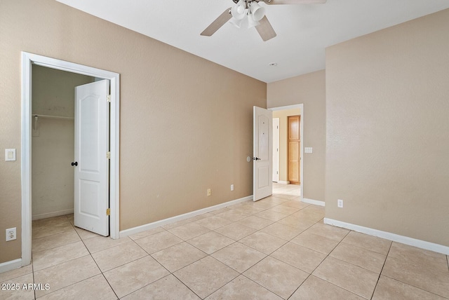 spare room featuring light tile patterned floors, ceiling fan, and baseboards