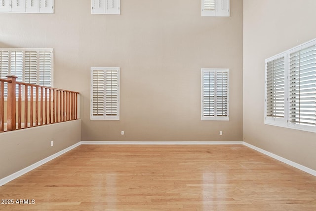 unfurnished room featuring a high ceiling, wood finished floors, and baseboards