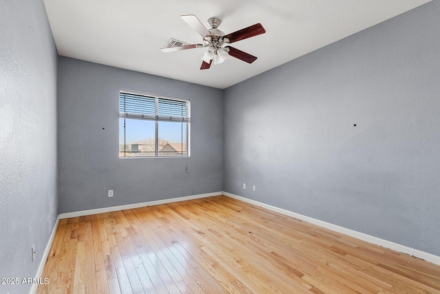 unfurnished room with visible vents, hardwood / wood-style floors, a ceiling fan, and baseboards