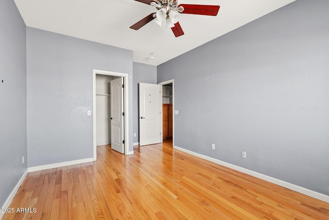 unfurnished bedroom featuring baseboards, ceiling fan, a spacious closet, light wood-type flooring, and a closet