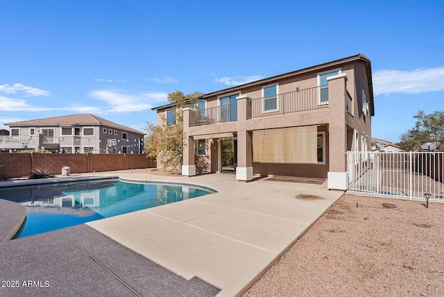 back of house with a patio, a balcony, fence, a fenced in pool, and stucco siding