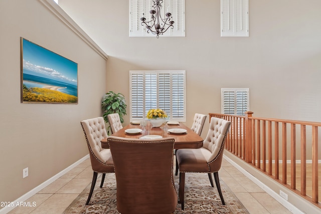 tiled dining space with an inviting chandelier, a high ceiling, and baseboards