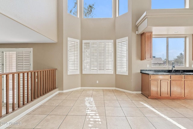 kitchen with dark countertops, a sink, baseboards, and light tile patterned floors