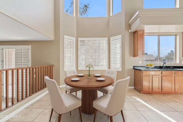 dining room with light tile patterned floors, a high ceiling, and baseboards