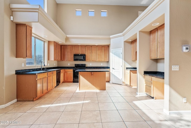 kitchen with dark countertops, black appliances, a kitchen island, and light tile patterned floors