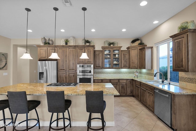 kitchen with pendant lighting, a kitchen island, sink, and appliances with stainless steel finishes