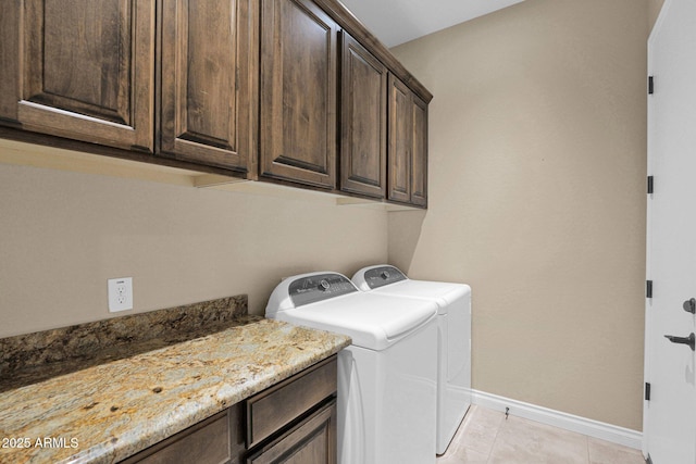 laundry room featuring washer and clothes dryer, light tile patterned floors, and cabinets