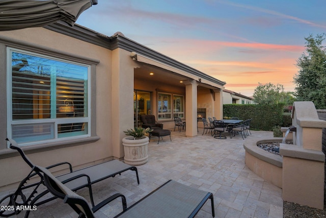 patio terrace at dusk with exterior fireplace