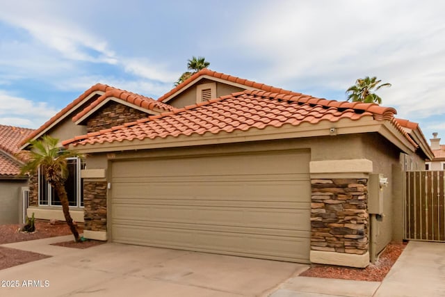 mediterranean / spanish house with concrete driveway, stone siding, stucco siding, and a garage