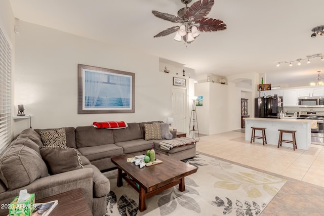 living room featuring light tile patterned flooring, visible vents, a ceiling fan, and arched walkways