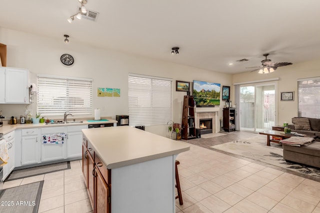 kitchen with a sink, visible vents, light countertops, open floor plan, and light tile patterned flooring