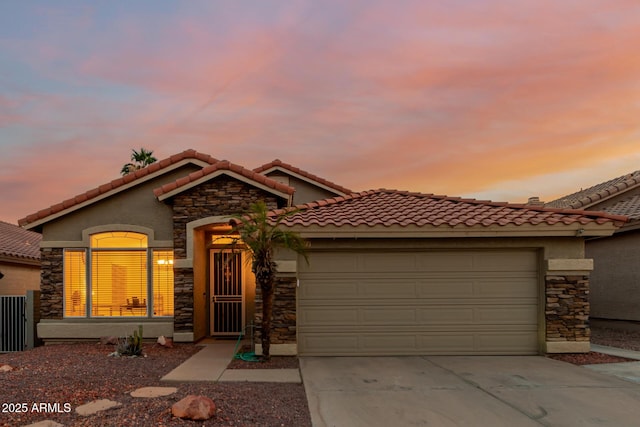 mediterranean / spanish home featuring a garage, a tile roof, concrete driveway, and stone siding