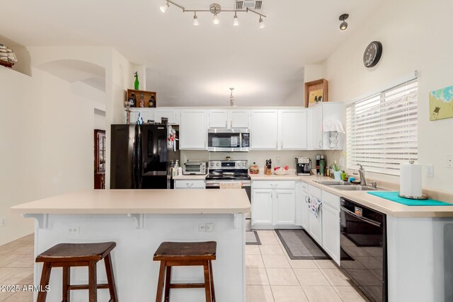 kitchen featuring light tile patterned floors, black appliances, a kitchen breakfast bar, and a sink