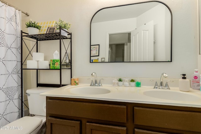full bath with toilet, double vanity, and a sink