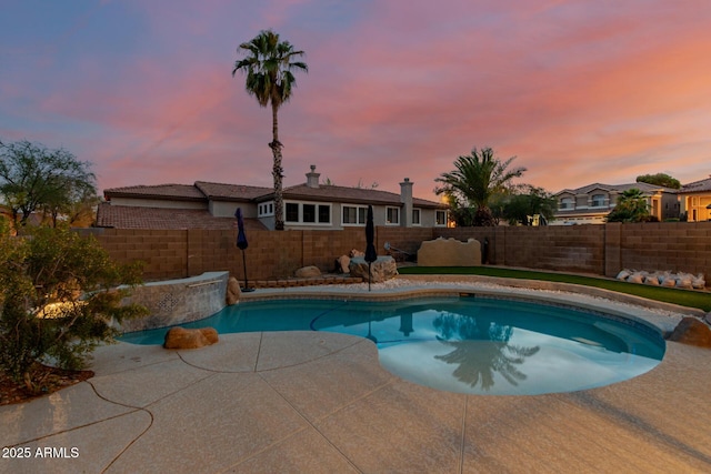 pool at dusk featuring a fenced in pool, a fenced backyard, and a patio area