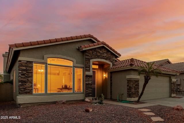 view of front facade with stucco siding, a tiled roof, stone siding, concrete driveway, and an attached garage