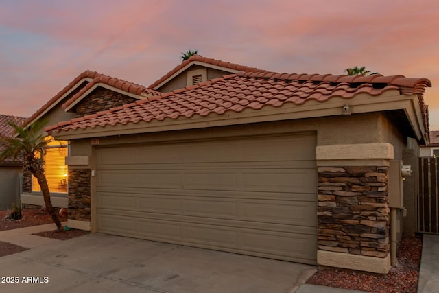 view of front of house featuring driveway, stone siding, stucco siding, and a garage