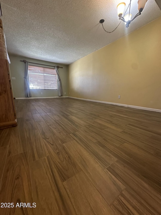 unfurnished room featuring hardwood / wood-style flooring, a textured ceiling, and an inviting chandelier