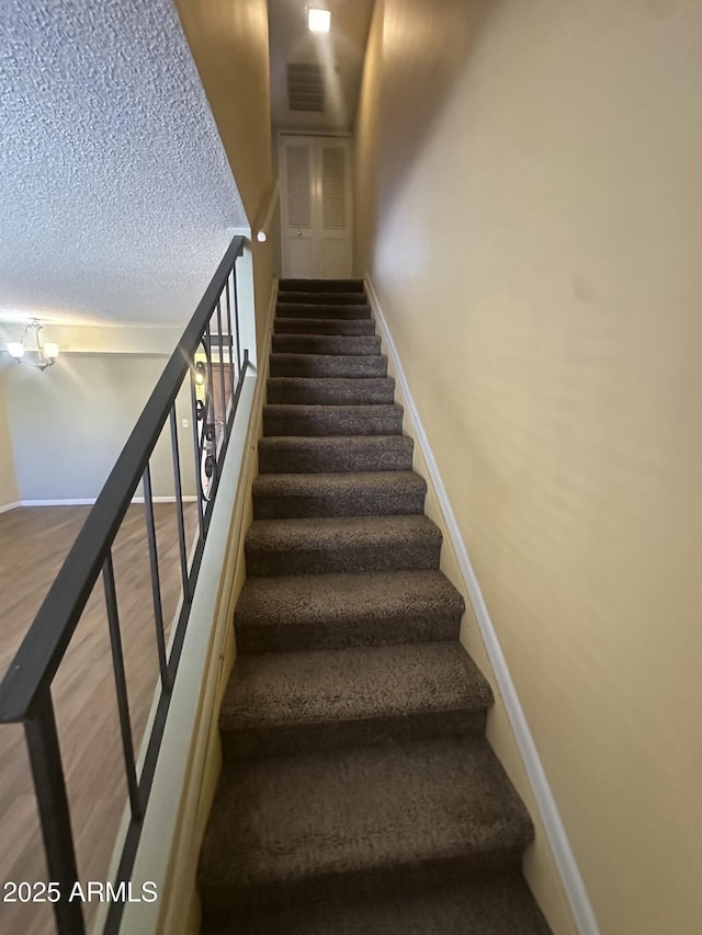 stairway featuring a textured ceiling