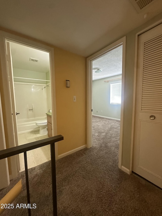 hallway featuring dark carpet and a textured ceiling