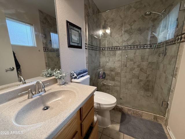 bathroom with a textured wall, toilet, vanity, and a shower stall