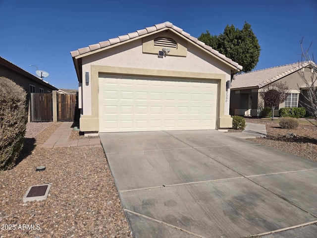 view of front facade with concrete driveway, fence, a tile roof, and stucco siding