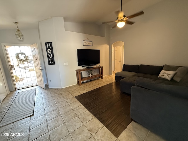 living room with a ceiling fan, arched walkways, lofted ceiling, and baseboards