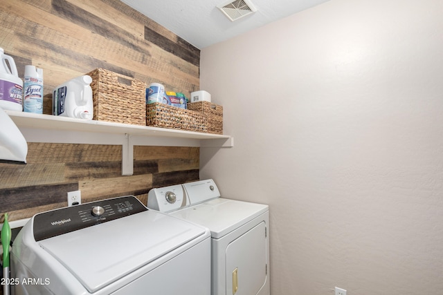 washroom featuring wood walls and separate washer and dryer